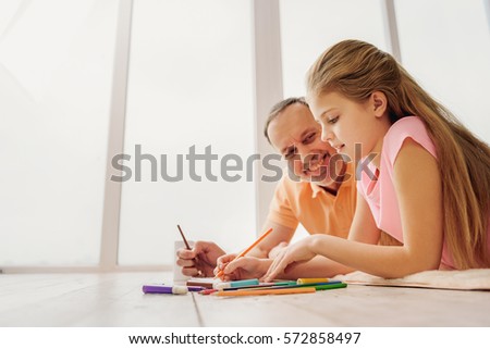 Cheerful granddaughter drawing with her grandparent