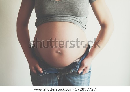 Pregnant woman trying to wear her jeans