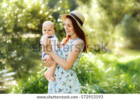 Pretty Young mother in hat with newborn baby boy, sunny nature background

