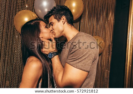 Shot of romantic young couple kissing in the night club. Man and woman in the pub. Royalty-Free Stock Photo #572921812