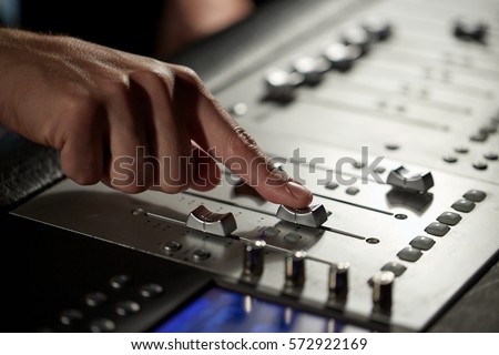 music, technology, people and equipment concept - hand using mixing console in sound recording studio