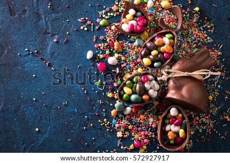 Delicious chocolate easter eggs ,bunny and sweets on dark blue background Royalty-Free Stock Photo #572927917