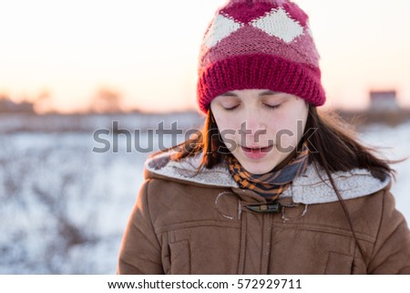 Teenage girl enjoys bright sunset lights in winter
