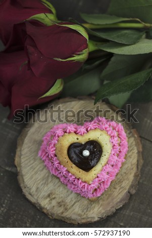 Heart shaped cupcake with pink icing and ganache filling, garnished with red roses.
