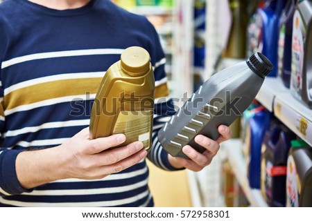 Man choices engine oil in the supermarket Royalty-Free Stock Photo #572958301