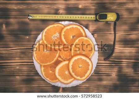 dish of sliced oranges on burnt wooden desk with measurement tape. food pattern - vintage film effect