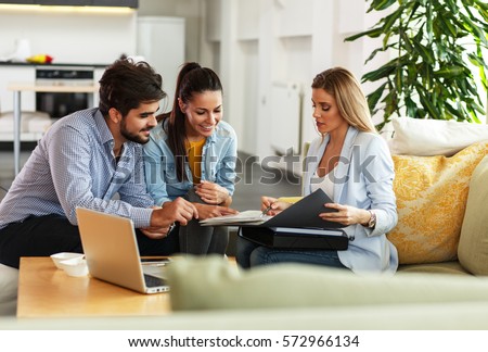 Female Real Estate agent offer home ownership and life insurance to young couple. Royalty-Free Stock Photo #572966134