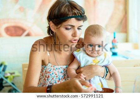 Young mother with her little baby in a restaurant. 