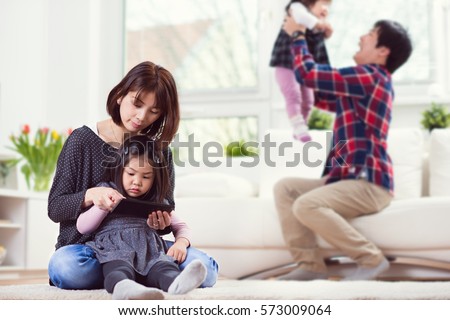 Young happy family with pretty daughters playing together and having fun at home