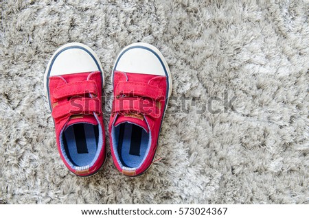 Red kid sneaker on gray mat.