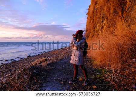 Nature photographer. young woman hiker photographs sunrise on the seashore