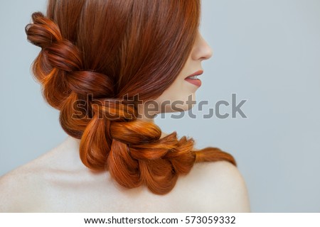 Beautiful girl with long red hair, braided with a French braid, in a beauty salon. Professional hair care and creating hairstyles. Royalty-Free Stock Photo #573059332