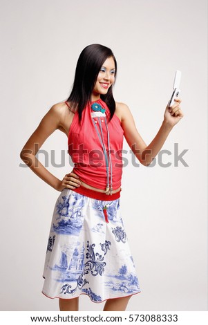 Young woman looking at mobile phone, hand on hip