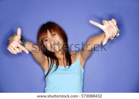Young woman making hand signs, looking at camera, smiling
