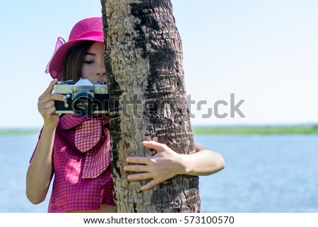 Happy young woman with vintage camera in the coconut park.
