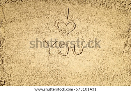 Top view of sandy beach with drawing in the sand or symbol. Background with copy space and visible sand texture.