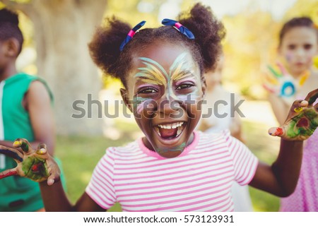 Portrait of a girl with make-up showing her painted hands in a park Royalty-Free Stock Photo #573123931
