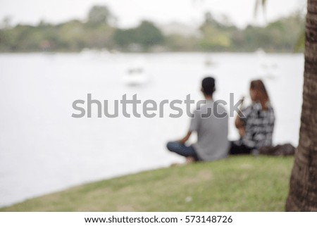 Blurred background of lovers sitting near the lake in the park