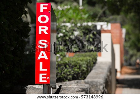 Conceptual image of red Real Estate For Sale sign advertising Private Property House or Apartment, blurred residential background, copy space.