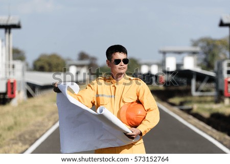Solar power plant. Engineer and worker work in solar power plant  on a background of photovoltaic panels with construction plan