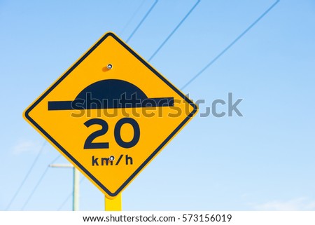 Street sign with speed bump symbol black on yellow and slow down Warning for road traffic, powerline and blue sky background, copy space.