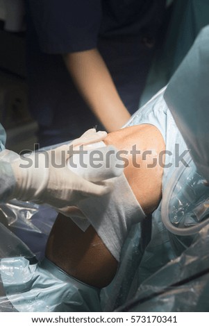 Nurse bandaging after knee surgery hospital operation medical procedure in emergency room operating theater.