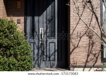 A tree foreground with blur background of house door.