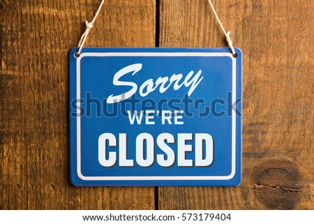" Sorry we're closed " sign in blue and white, on rustic wooden wall. Royalty-Free Stock Photo #573179404