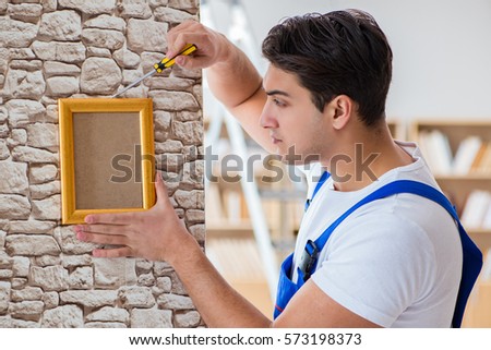 Repairman putting picture frame onto wall