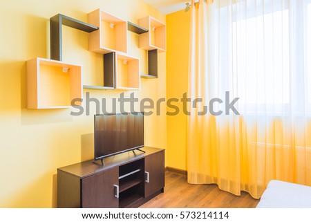 The interior of the living room in orange tones with TV