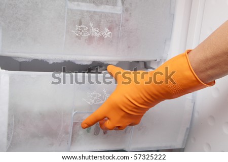Hand in glove opening refrigerator. Royalty-Free Stock Photo #57325222