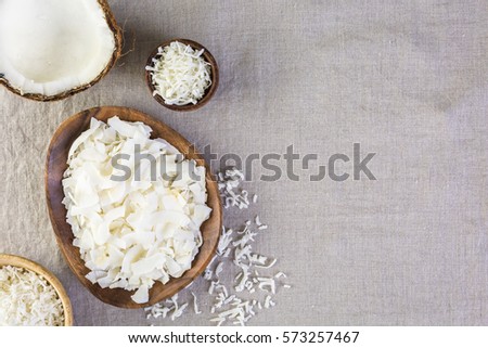 Dehydrated coconut flakes in wooden bowl. Royalty-Free Stock Photo #573257467