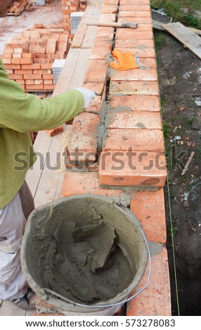Bricklayer Worker Installing Red Blocks and Caulking Brick Masonry Joints Exterior Wall with Trowel putty Knife. Bricklaying Masonry. Brick masonry. Bricklaying Stock Photo.