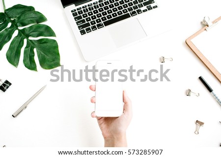 Mockup of mobile phone with blank copy space screen in female hand. Flat lay, top view workspace