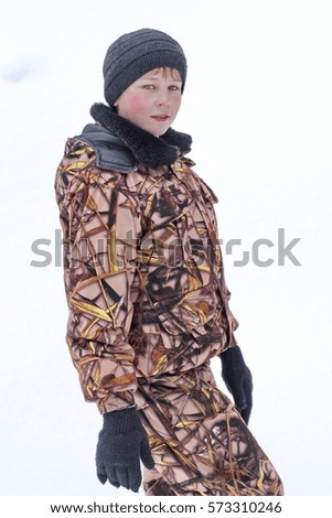 Walk in nature with a boy in the winter. Portrait of a boy wearing camouflage clothes and winter hat.