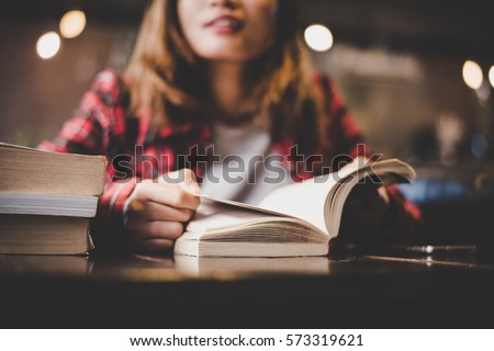 Hipster woman teenager sitting enjoy reading book at cafe. Vintage filter toned. Royalty-Free Stock Photo #573319621