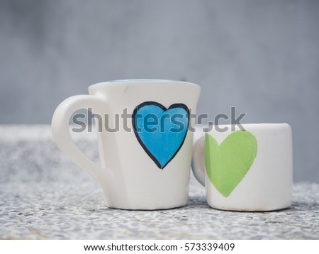 two white cups and size on marble table with blue and green heart printed Royalty-Free Stock Photo #573339409