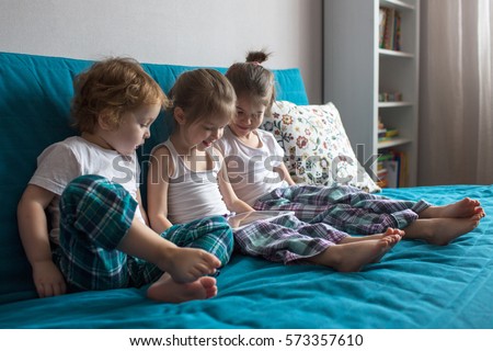 children sit on the couch, playing and watching cartoons  tablet