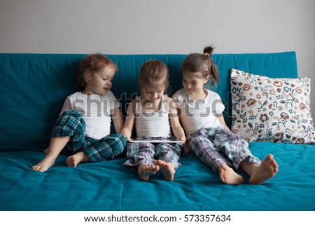 children sit on the couch, playing and watching cartoons  tablet
