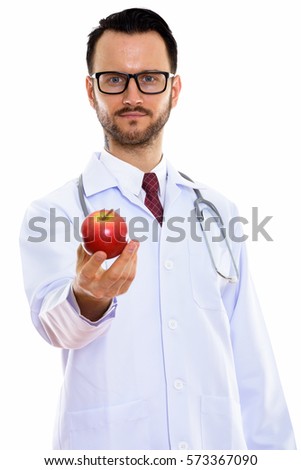 Studio shot of young man doctor giving red apple