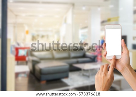 woman use mobile phone and blurred image of furniture shop in shopping mall