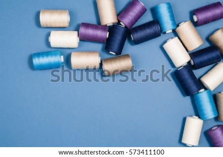 Top view of colorful thread spools over blue seamless background. Image taken from above.