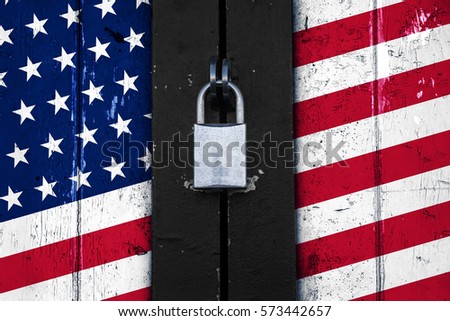 United states of america flag painted on a wooden door and locked with a padlock, political concept background, symbol for protectionism  Royalty-Free Stock Photo #573442657