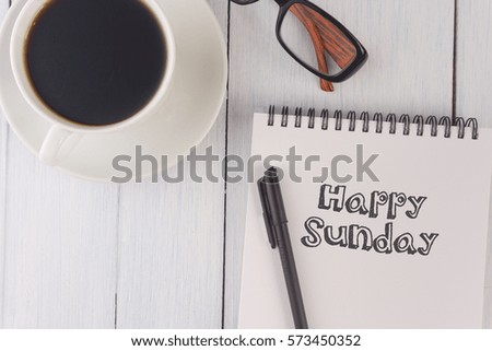 top view of happy sunday written on notebook,pen,coffee,glasses on the white desk