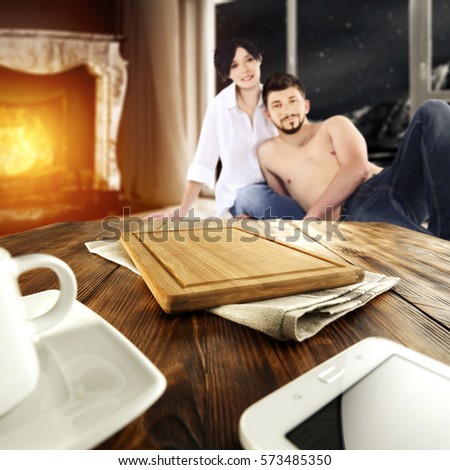 Wooden desk of free space for your decoration and two lovers on floor in room with fireplace and big window 