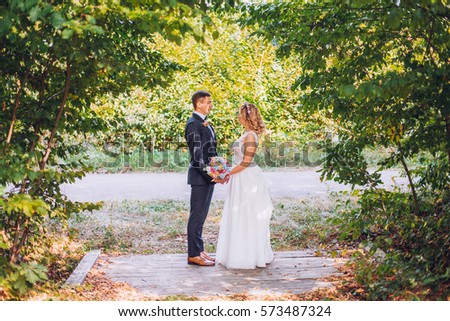Just married loving hipster couple in wedding dress and suit on green field in a forest at sunset. happy bride and groom walking running and kissing in the summer meadow. Romantic Married young family