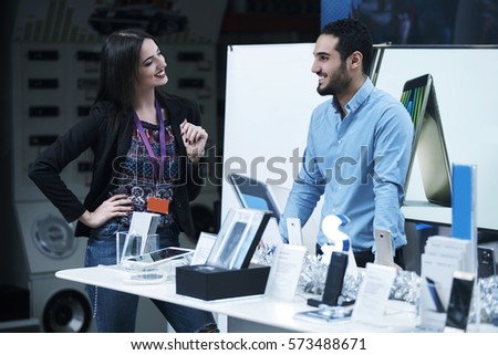 Young couple in consumer electronics store looking at latest laptop, television,mobile and photo camera