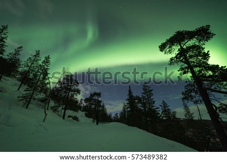 Snowy landscape and Northern lights dancing in Lapland, Finland.