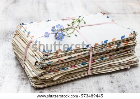 Stack of vintage love letters and forget me not flowers.