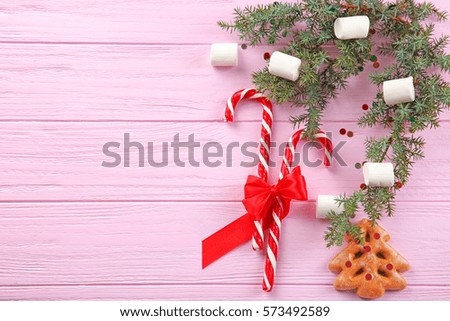 Christmas decorations and candies on pink wooden background